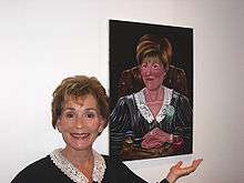 Judge Judy stands next to a portrait of herself